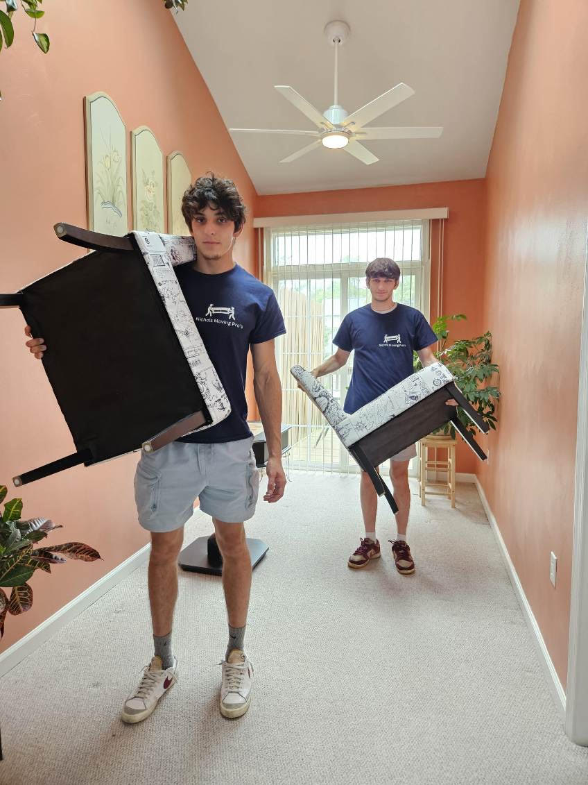 Team of movers carrying furniture into a house.